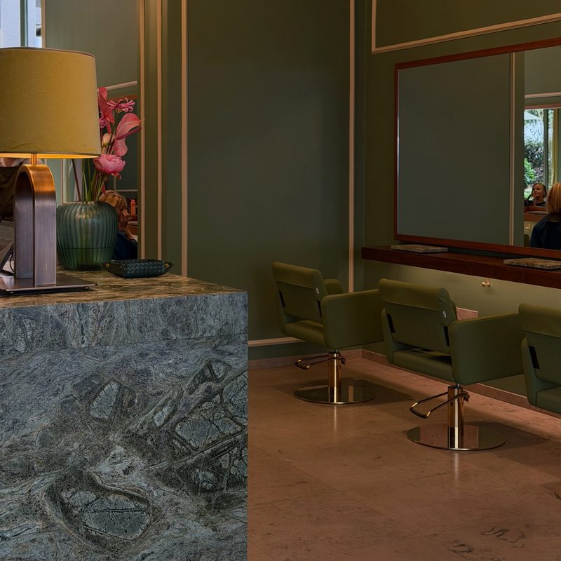 Salon-Innenraum mit Marmortheke und grünen Stühlen